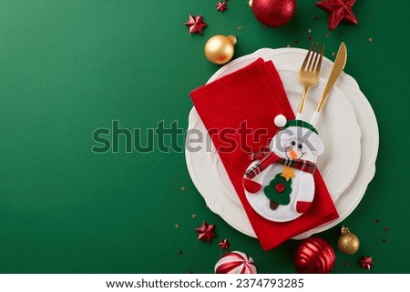 A holiday-themed tablescape that takes your breath away. Top view photo of plates, cutlery, xmas balls, red napkin, snowman, stars confetti on green background with ad space