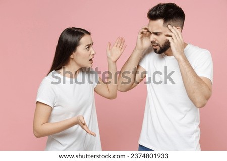 Young irritated dissatisfied couple two friends man woman in white basic t-shirts quarrel swearing have problem stress need family psychologist isolated on pastel pink color background studio portrait Royalty-Free Stock Photo #2374801933