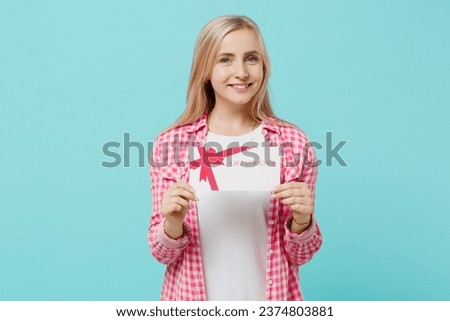 Young happy woman she 30s wears pink shirt white t-shirt hold gift certificate coupon voucher card for store isolated on plain pastel light blue background studio portrait. People lifestyle concept