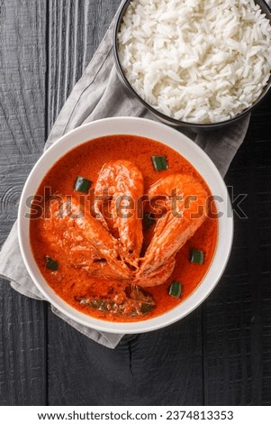 Chingri Macher Malai Curry is a traditional Bengali cooked with sauteed tiger prawns in a mildy spiced coconut milk based curry sauce closeup on the plate on the wooden table. Vertical top view
 Royalty-Free Stock Photo #2374813353