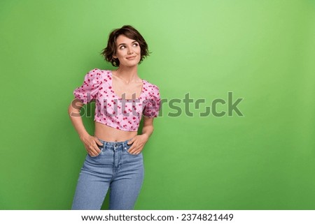Portrait of nice cute girl with short haircut wear stylish blouse look empty space palms in pockets isolated on green color background