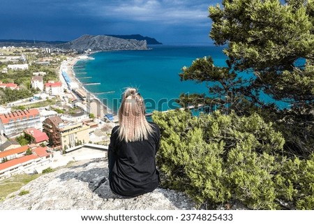 A girl on the background of a view from the Genoese fortress to the Sudak Bay. Sudak May 2021 Royalty-Free Stock Photo #2374825433