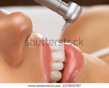 A dentist doctor treats caries on a tooth of a young beautiful woman in a dental clinic. Tooth filling. Royalty-Free Stock Photo #2374833787