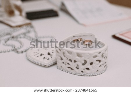wedding rings inside a heart-shaped porcelain box Royalty-Free Stock Photo #2374841565