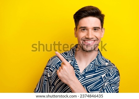 Portrait of positive guy with brunet hair bristle wear print shirt indicaitng at sale empty space isolated on yellow color background