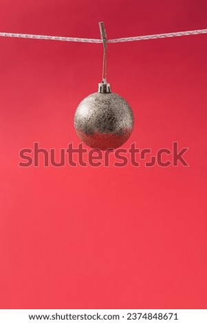 Creative background with a golden Christmas ball hanging on a wooden clip against a red background. Holiday concept.