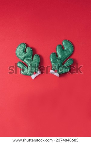 Green Reindeer antlers on red background with copy space. Christmas minimal background. Greeting card.