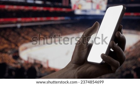 CU African-American Black male using phone during ice hockey game, indoor arena. Betting online