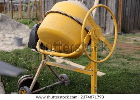 Yellow concrete mixer in the courtyard of a house on green grass