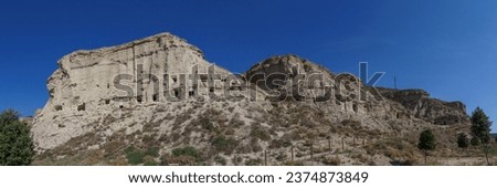 Panorama picture of human made caves inside the rock of a hill in Arguedas, Bardenas Reales, Navarra, Spain