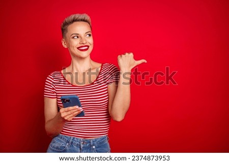 Photo of sunning girl blogger in trendy striped clothes demonstrate empty space recommend iphone samsung isolated on red color background