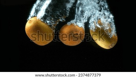 Kiwi Fruits, actinidia chinensis, Fruits falling into Water against Black Background