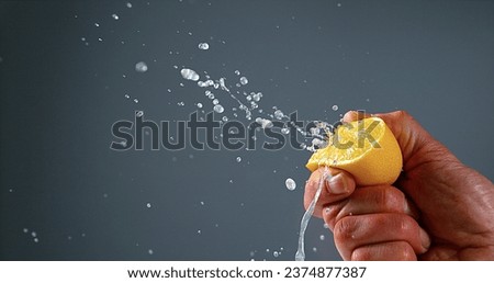 Hand of Man Squeezing Lemon, citrus limonum against Black Background Royalty-Free Stock Photo #2374877387