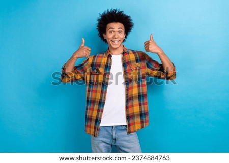 Photo of satisfied optimistic guy with perming coiffure wear plaid jacket showing thumbs up approve isolated on blue color background