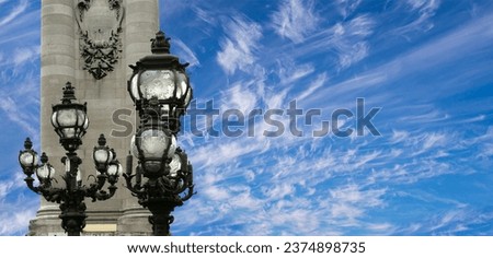 Lamp posts on Alexander III Bridge against the background of a beautiful sky with clouds. Paris, France. This arch bridge is one of the most beautiful river crossings in the world