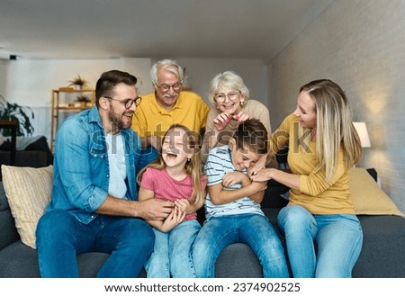 Portrait of a three generation famili, grandparents, parents and children sitting on sofa and having fun posing at home Royalty-Free Stock Photo #2374902525