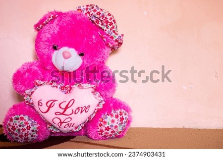 Pink teddy bear carries a heart shape