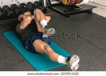 A young man doing a set of bicycle crunches on a mat. Abdominal and core workout exercise at the gym. Royalty-Free Stock Photo #2374911429