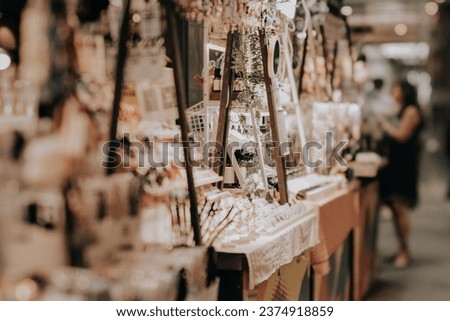 Indoor festive weekend market. Social pop up event of entrepreneurs and makers selling their goods at their booths in shopping mall. Captured with a tilt-shift lens. Selective focus; bokeh effect. Royalty-Free Stock Photo #2374918859