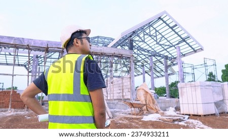 Back image of Male engineer white safety equipment working at construction site