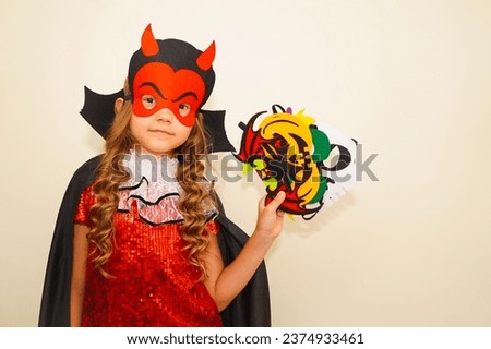 Unique child. Halloween. Child in Halloween carnival mask. The child made handmade felt masks for Halloween. Kid in a devil costume. Girl prepared for Halloween celebration. Bat, pumpkin, witch masks