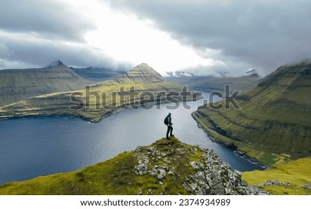 Man silhouette on background Funningur fjord from the Funningur top. Eysturoy Island, Faroe islands. Tourist explores natural attractions Royalty-Free Stock Photo #2374934989