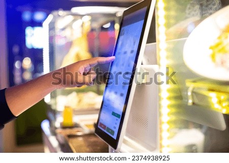 Selective focus to customer's hand is touching a touch screen to order food and pay electronically.