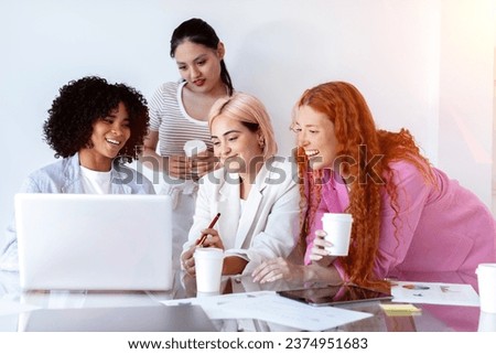 Four smiling girls, focused and creative, gathered around a computer, exuding a professional and collaborative work atmosphere. Multiracial group of young women working or studying together with pc. Royalty-Free Stock Photo #2374951683