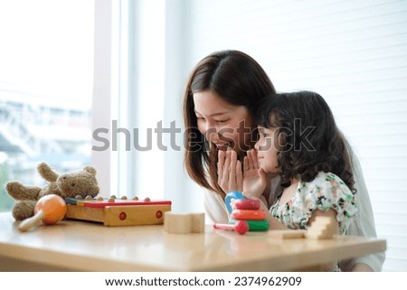 Cute little girl pretends to whisper to her mother about new toy she wants.Child play with her mom. Royalty-Free Stock Photo #2374962909