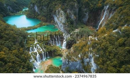 Waterfalls in the autumn forest flowing into lakes. Tourists visit famous Plitvice park in Croatia. Mountain streams with clear water. Royalty-Free Stock Photo #2374967835