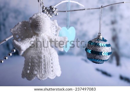 Knitted Christmas angel hanging on bud on light background 