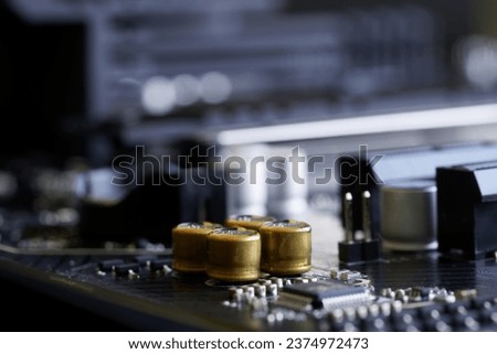 Golden capacitors built into the black motherboard of a modern computer. Photo. Macro Shallow depth of field. Selective focus. Close-up