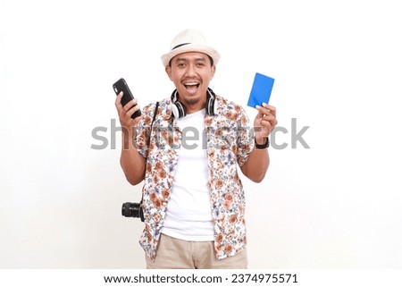 Excited Asian man traveler standing while holding passport and cell phone. Isolated on white background with copyspace