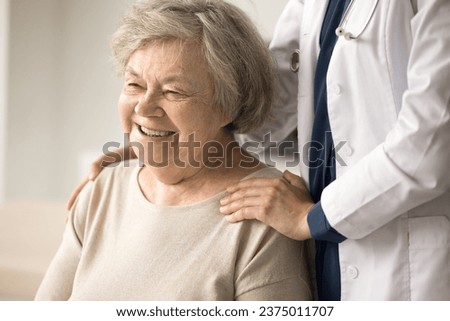 Close up portrait of happy female pensioner enjoy professional medical care in clinic. Woman physician support older patient touch shoulders, give psychological aid. Geriatrics, healthcare, services