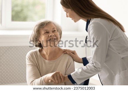 Young female doctor in uniform support old patient hold her palm, give hope, congratulate with good treatment result. Happy aged lady visit therapist for health check up. Professional medical services