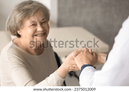 Close up smiling old woman hold doctors hand, get optimistic news after therapy. Therapist supports, encourages old patient, give hope, congratulate with end of treatment. Geriatrics, medical services Royalty-Free Stock Photo #2375012009