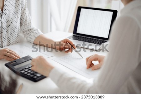 Accountant using a calculator and laptop computer for counting taxes with a client or a colleague at white desk in office. Teamwork in business audit and finance
