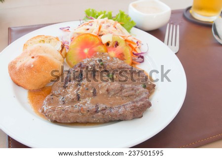 Succulent thick juicy portions of grilled fillet steak served with tomatoes and roast vegetables on an old wooden board 