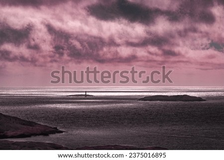 Beautiful view and sea scape over a  striped Skagerrak Sea, a light house and islands along the coast line. Cloudy skies causing the sun to highlight areas on the sea level. Royalty-Free Stock Photo #2375016895