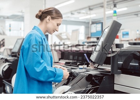 Worker confectioning electronic parts on assembly line Royalty-Free Stock Photo #2375022357