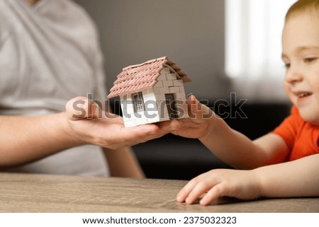 A father gives his son a small house. The concept of transfer of property and inheritance. Real estate. housing as a gift, apartment or house Royalty-Free Stock Photo #2375032323