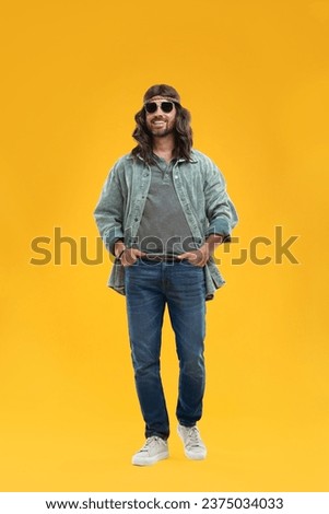 Stylish hippie man in sunglasses on orange background Royalty-Free Stock Photo #2375034033