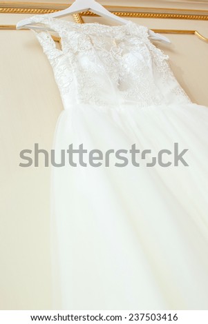White Wedding dress hanging on a shoulders. Soft light and colours