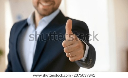 Young successful businessman in formal jacket showing thumb up like gesture, expressing satisfaction, approval, giving positive feedback, recommendation. Close up of arm, banner shot