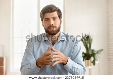 Serious handsome young business blogger man speaking at camera, giving training webinar, online lecture, talking on video call. Male professional vlogger head shot portrait