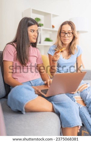 Vertical photo of students eating pizza while using laptop at home