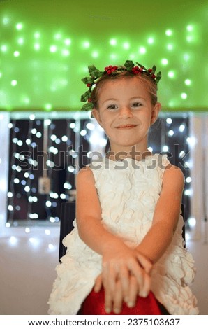 Cute little girl in a white dress with a Christmas wreath on her head