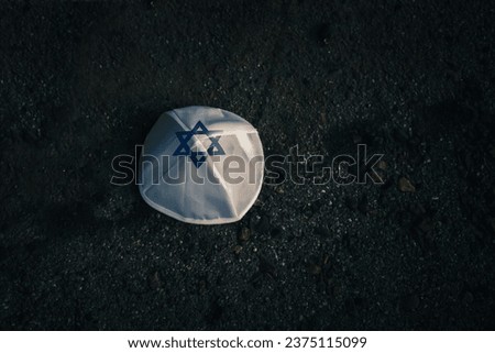 knitted kippah cap in the Israeli flag style on a dark asphalt road background
