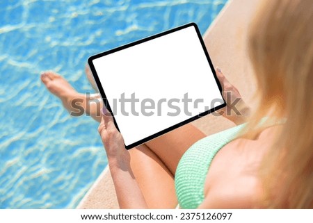 Woman holding tablet computer by the pool, view from above