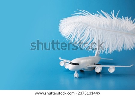 airplane and feather on a blue background, soft landing, easy and comfortable flight Royalty-Free Stock Photo #2375131449